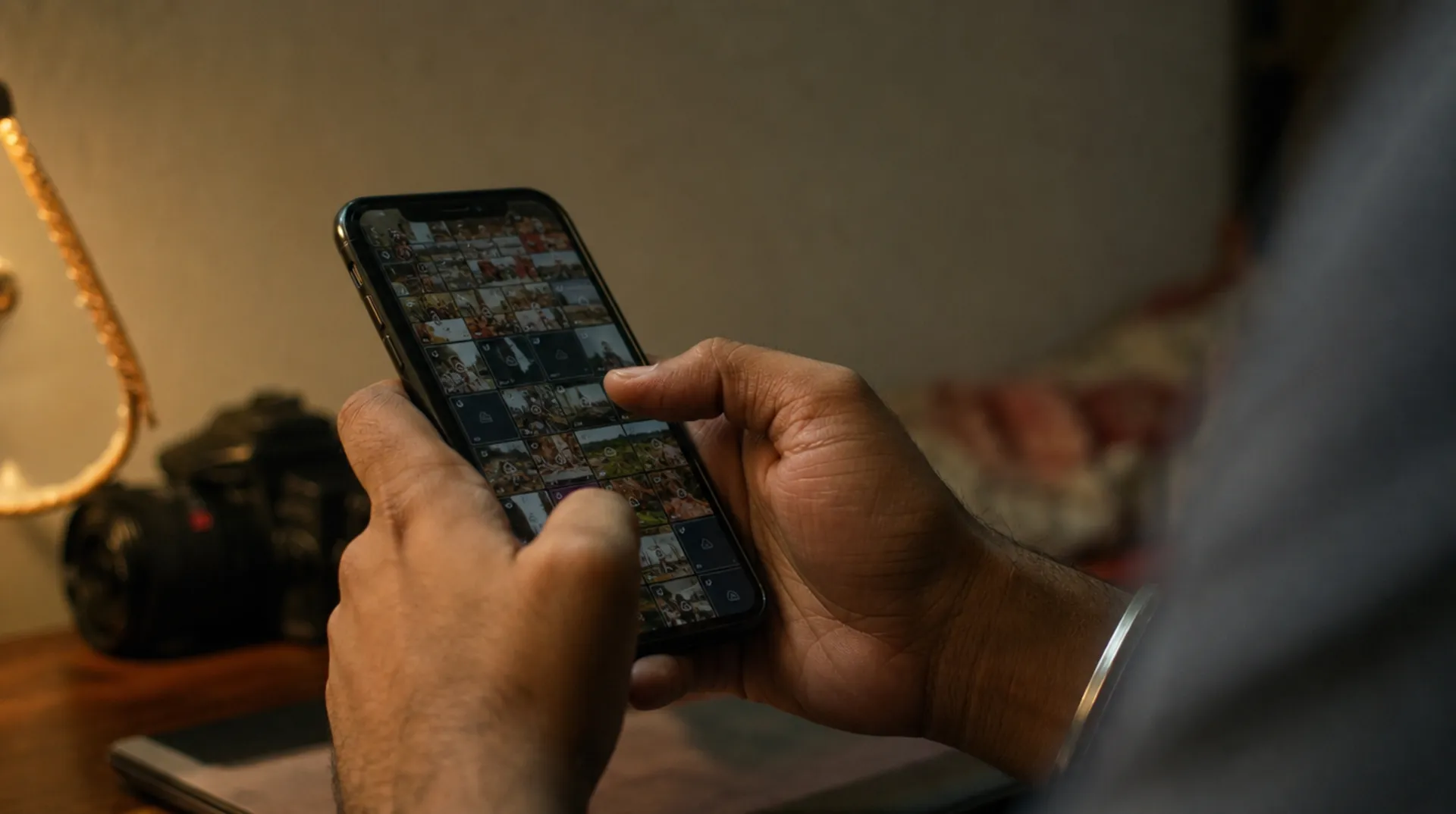 Close-up of hands scrolling an overloaded WhatsApp chat full of compressed photo thumbnails.